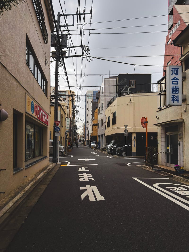 An empty backstreet with a stop sign painted on the road and power lines overhead.