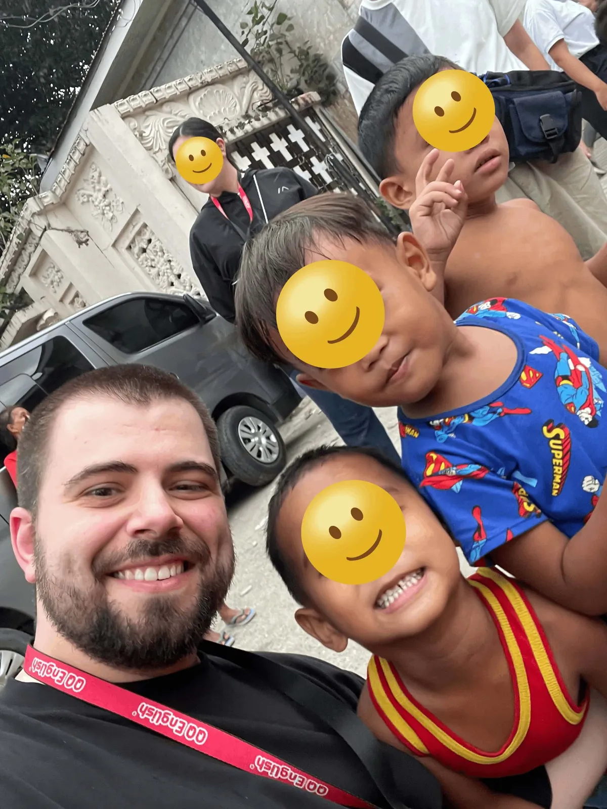 Goksel with children on a street in the Philippines, one child wearing a Superman shirt.